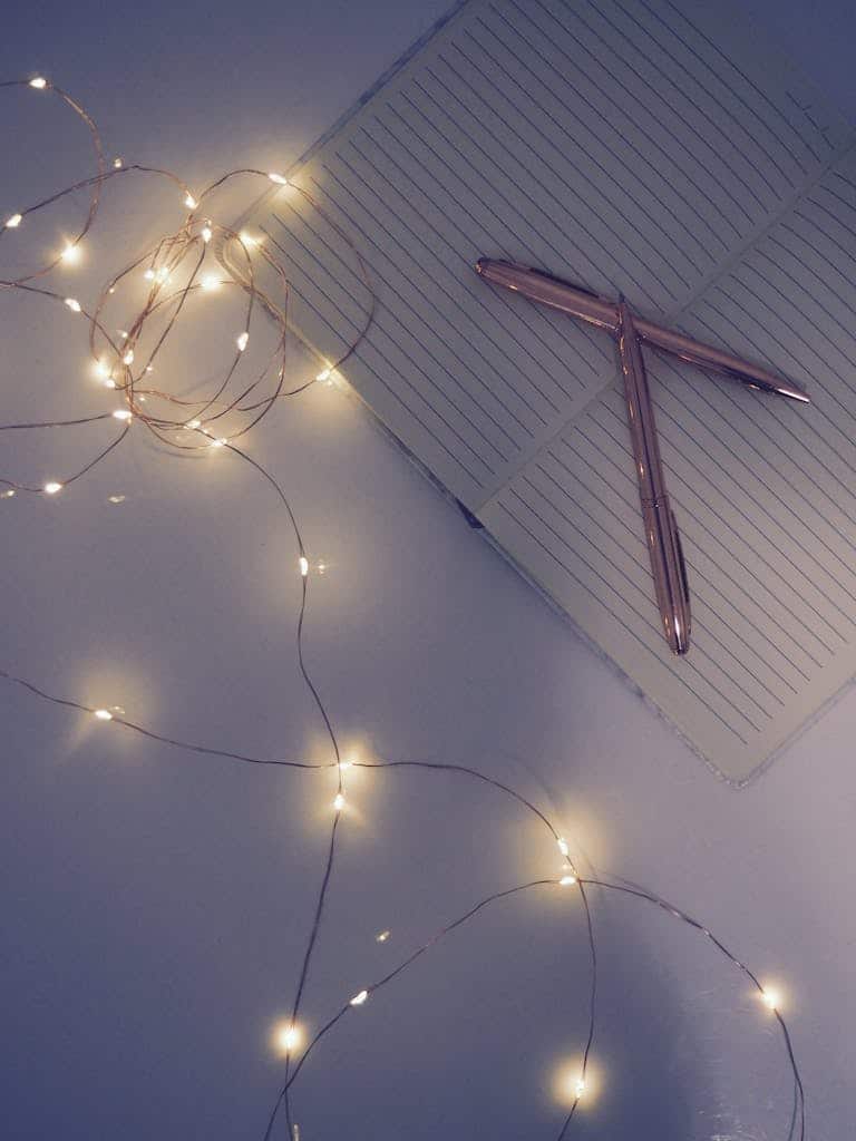 A notebook with string lights and pens in a cozy ambient setting, symbolizing self-care, reflection, and personal growth.