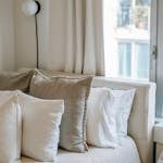 A serene and cozy bedroom setup featuring soft linen cushions and natural light.