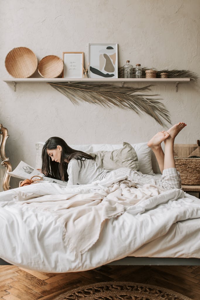 A woman is reading on a cozy bed in a chic and minimalist bedroom setting.