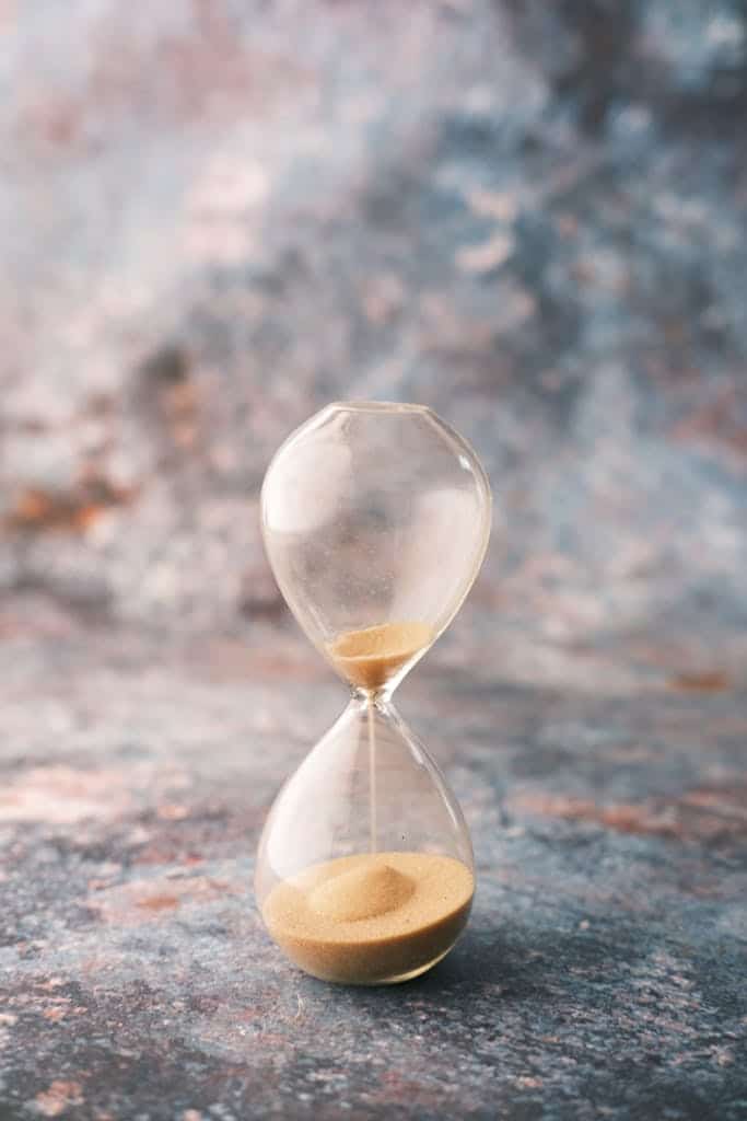 An elegant hourglass on a decorative textured surface, symbolizing the passage of time.