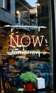 A colorful neon sign on a glass storefront with "Yesterday" and "Tomorrow" crossed out, leaving "Today" in the middle.