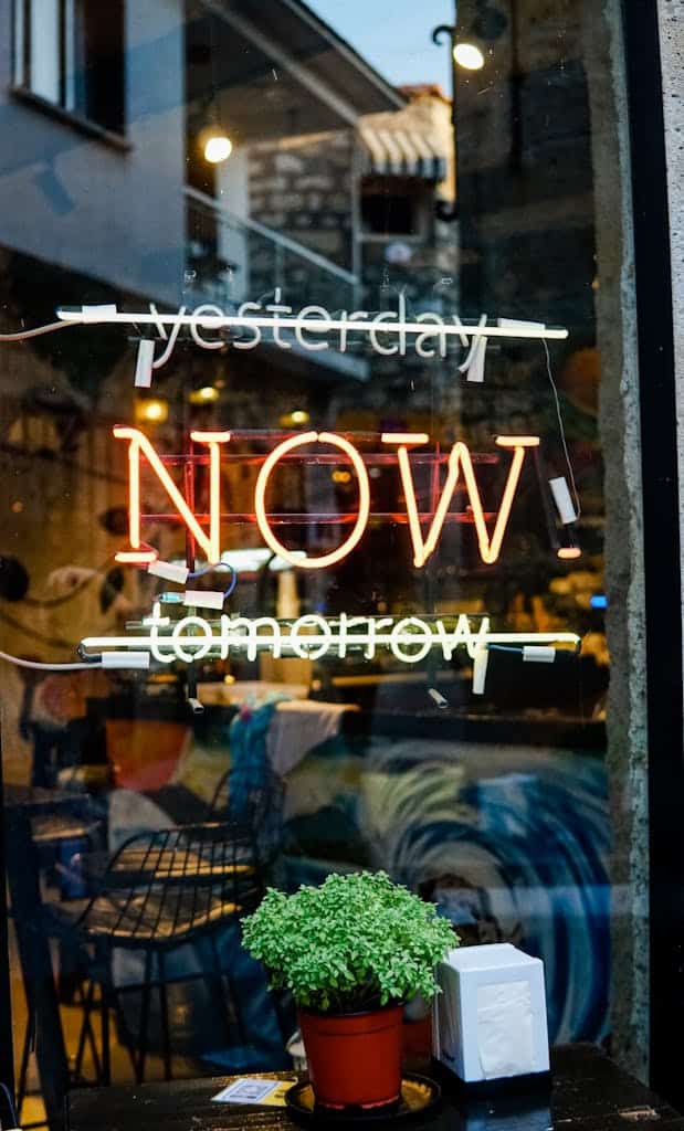 A colorful neon sign on a glass storefront with "Yesterday" and "Tomorrow" crossed out, leaving "Today" in the middle.