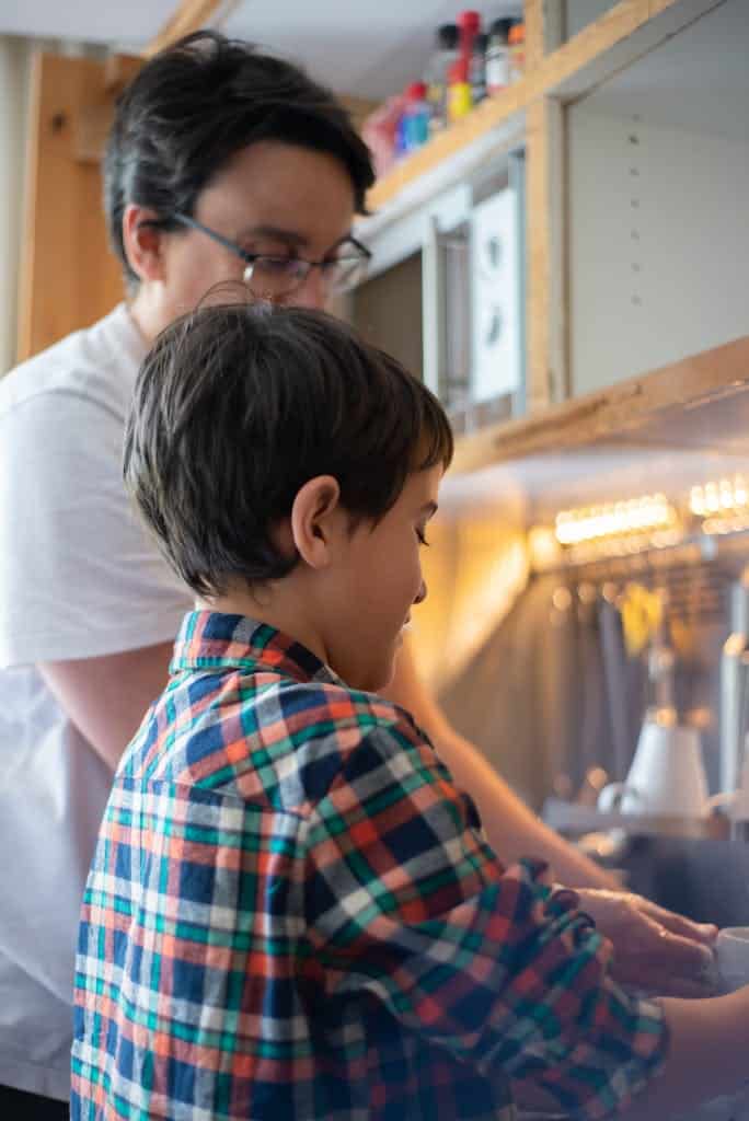 Father and son enjoy bonding over doing dishes in the kitchen, a daily routine.