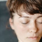 A natural, close-up portrait of a woman with eyes closed, highlighting her serene expression.