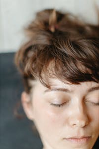 A natural, close-up portrait of a woman with eyes closed, highlighting her serene expression.