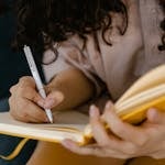 Woman writing in a yellow notebook to protect her peace