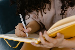Woman writing in a yellow notebook to protect her peace