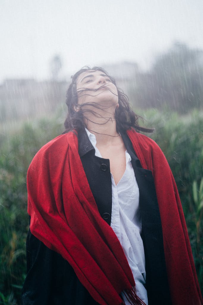 Portrait of a woman with closed eyes and long hair enjoying the rain outdoors.