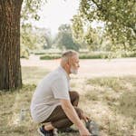 Senior man setting up yoga mat outdoors, promoting healthy lifestyle.